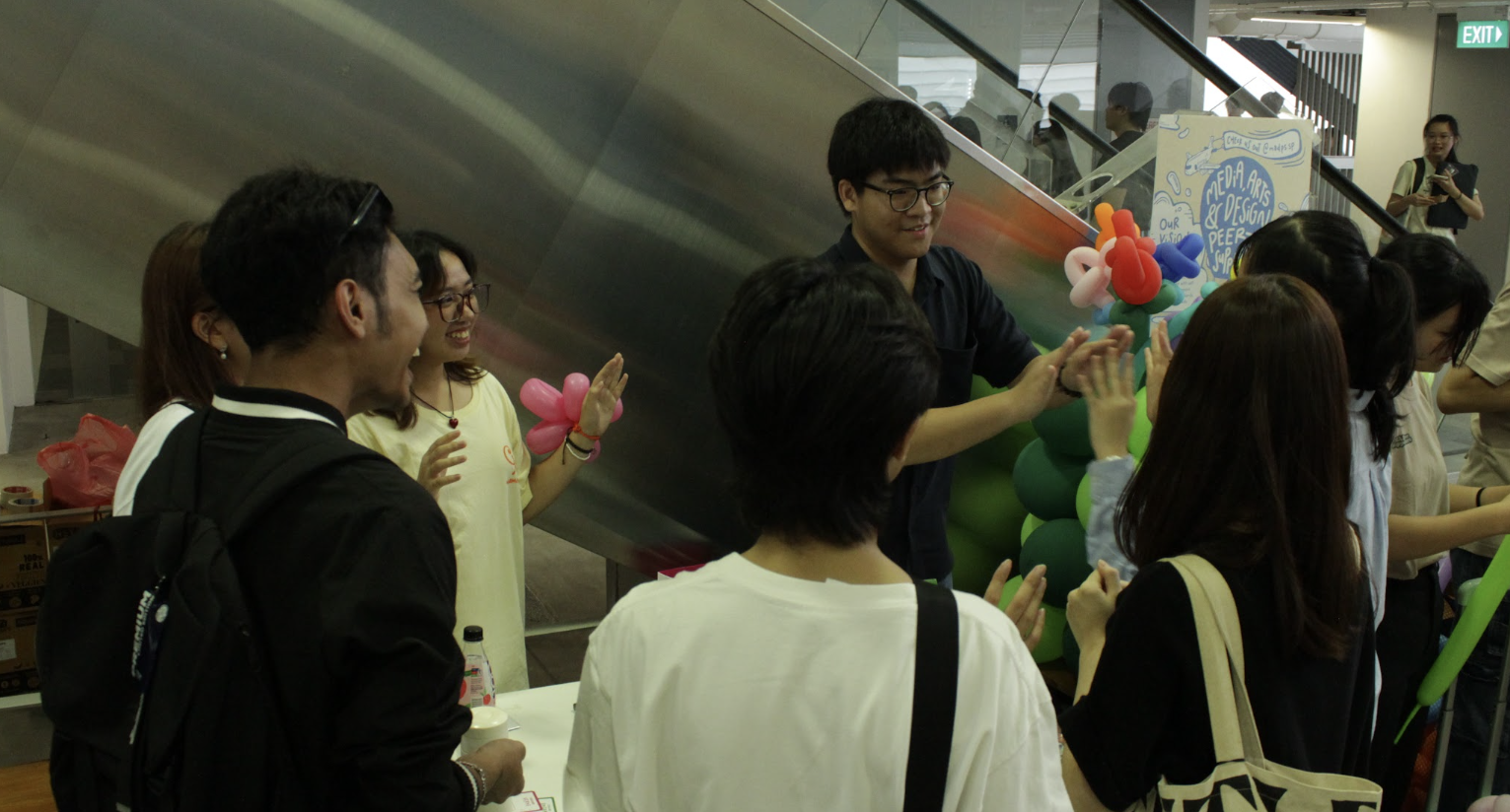 Students and visitors gathered around the Harmonics booth during a showcase event.